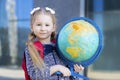 Kid back to school. Happy cute clever confident girl with in blue uniform go to first grade. Smart schoolchild with red schoolbag Royalty Free Stock Photo