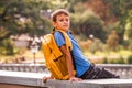 Kid with backpack sitting outdoors and looking to camera