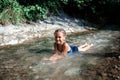 Kid baths in stream river in mountains, natural pool and spa. Cold water, wildlife. Green tourism