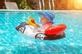 Kid behind the wheel in the pool. Summer vacation at sea. A little girl less than one year old is driving an inflatable boat in