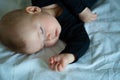Kid in black clothes is sleeping on a white bed Royalty Free Stock Photo