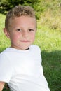 Kid blond boy child in white t-shirt in green grass field park home garden Royalty Free Stock Photo