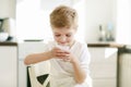 Kid or blonde happy boy eating at table. Childhood and happiness, independence. Breakfast, morning, family. Small boy Royalty Free Stock Photo