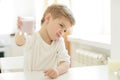 Kid or blonde happy boy eating at table. Childhood and happiness, independence. Breakfast, morning, family. Small boy Royalty Free Stock Photo