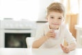 Kid or blonde happy boy eating at table. Childhood and happiness, independence. Breakfast, morning, family. Small boy Royalty Free Stock Photo