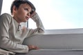 Kid boy of adolescence is at home leaned on windowsill and looks forward to the future Royalty Free Stock Photo