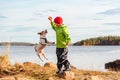 Kid boy balancing on stone playing with dog jumping high for toy. Family rests on beach on Autumn day Royalty Free Stock Photo
