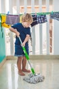 Kid boy cleaning room, washing floor with mop. Little home helper. Montessori concept
