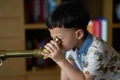 Kid or boy concentrates telescope indoors in night time