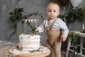 kid boy eating cake on his first birthday, one year old child delicious cake, decorated background in natural style