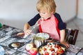 Kid boy helping and baking apple pie in home''s kitchen Royalty Free Stock Photo