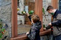 Kid boy and his father feeding parrots in zoological garden. Child and middle-aged man playing and feed trusting