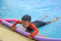 Kid or boy hold foam noodle on swimming pool side bar to float d Royalty Free Stock Photo