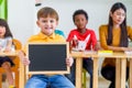 Kid boy holding blackboard with back to school word with diversity friends and teacher at background,Kindergarten school,mock up Royalty Free Stock Photo