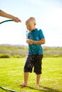 Kid, boy and hose pipe with splash, water fun and playing outdoor in backyard or garden for sunshine. Child, male and Royalty Free Stock Photo