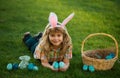 Kid boy lying on the grass and finding easter eggs. Child with easter eggs and bunny ears, outdoor portrait. Bunny kids Royalty Free Stock Photo