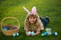 Kid boy lying on the grass and finding easter eggs. Child with easter eggs and bunny ears, outdoor portrait. Bunny kids Royalty Free Stock Photo