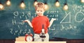 Kid boy near microscope, clock in classroom, chalkboard on background. First former confused with studying, learning