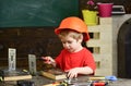 Kid boy in orange hard hat or helmet, study room background. Boy play as builder or repairer, work with tools. Child Royalty Free Stock Photo
