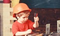 Kid boy in orange hard hat or helmet, study room background. Boy play as builder or repairer, work with tools. Childhood Royalty Free Stock Photo