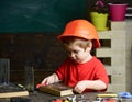 Kid boy in orange hard hat or helmet, study room background. Childhood concept. Boy play as builder or repairer, work Royalty Free Stock Photo