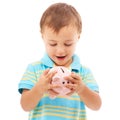 Kid, boy and piggy bank for change, finance and smiling in studio by white background. Happy male person, child and