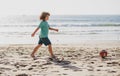 Kid boy play football on sand beach. Summer soccer on beach for children.