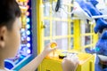 Kid boy playing claw crane machine,fun enjoy,arcade game with toys inside,little child catching the doll during shopping in a mall