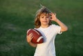 Kid boy playing with rugby ball in park. Kid boy having fun and playing american football on green grass park. Royalty Free Stock Photo