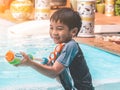 Kid boy is playing with splash water gun on a swimming pool in Thailand tropical resort Royalty Free Stock Photo