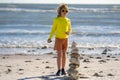 Kid boy playing with stones on the beach. Child play with pyramid of stones on the beach, sea seascape, rest and seaside Royalty Free Stock Photo