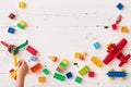 The kid boy plays in multi-colored cubes on a white wooden table. Top view on colored toy bricks Royalty Free Stock Photo