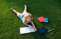 Kid boy reading interest book and writing on notebook in the garden. Summertime fun. Cute boy lying on the grass reading Royalty Free Stock Photo