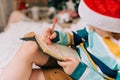 Kid boy in red Santa hat writing the letter and drawing to dear Santa at home. Child wish list. Dreams of a Christmas Royalty Free Stock Photo