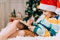 Kid boy in red Santa hat writing the letter and drawing to dear Santa at home. Child wish list. Dreams of a Christmas Royalty Free Stock Photo