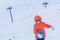 Kid boy running along the road with snow in winter. Happy laughing child, cute boy in a colorful snowsuit and snow Royalty Free Stock Photo