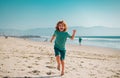 Kid boy running and jumping in summer sandy beach.
