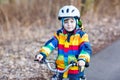 Kid boy in safety helmet and colorful raincoat riding bike, outd Royalty Free Stock Photo