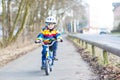 Kid boy in safety helmet and colorful raincoat riding bike, outd Royalty Free Stock Photo