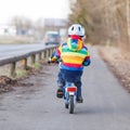 Kid boy in safety helmet and colorful raincoat riding bike, outd Royalty Free Stock Photo