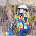 Kid boy in safety helmet and colorful raincoat riding bike, outd Royalty Free Stock Photo