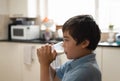 Kid boy standing in kitchen drinking grass of warm milk for breakfast before go to school. Healhty food liftstyle for children Royalty Free Stock Photo