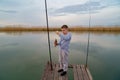 A kid boy on a wooden bridge and catches a fish on fishing rod. Royalty Free Stock Photo