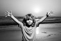 Kid boy on sunset beach, raised hands. Amazed surprised kids emotions.