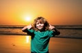 Kid boy on sunset beach, thumbs up. Amazed surprised kids emotions.