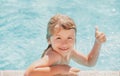 Kid boy swim in swimming pool with thumbs up. Happy little kid boy playing with in outdoor swimming pool on hot summer Royalty Free Stock Photo