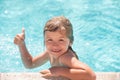 Kid boy swim in swimming pool with thumbs up. Happy little kid boy playing with in outdoor swimming pool on hot summer Royalty Free Stock Photo