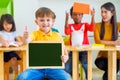 Kid boy thumbs up and holding blackboard with back to school word with diversity friends and teacher at background,Kindergarten s