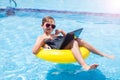 Kid boy using laptop in the swimming pool. Technology, summer and vacation concept Royalty Free Stock Photo