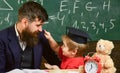 Kid cheerful distracting while studying, attention deficit. Naughty child concept. Teacher and pupil in mortarboard Royalty Free Stock Photo